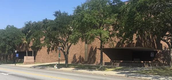 The long, low brick front of the Charleston Museum on Meeting Street, shaded by a row of trees