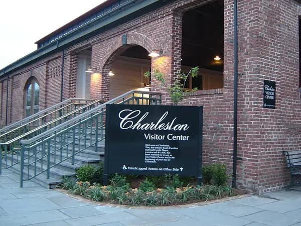 The brick Charleston Visitor Center with arched windows, ramps and a black sign reading Charleston Visitor Center