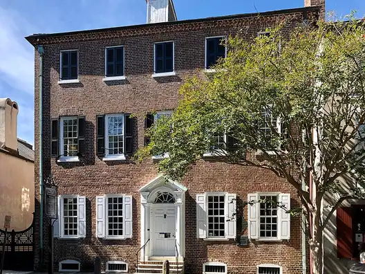 The three-story brick Heyward-Washington House with white window trim and a doorway on Church Street