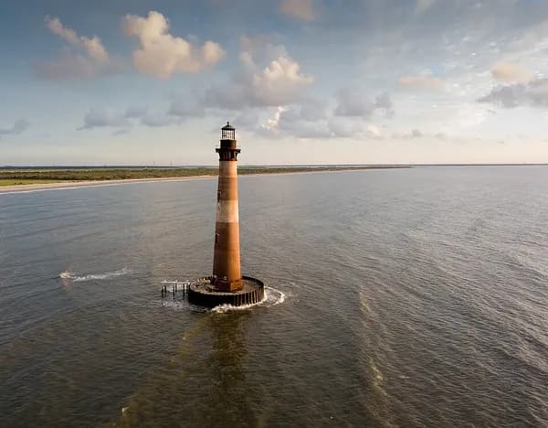 Aerial view of the Morris Island Lighthouse standing alone in the water off the north end of Folly Beach