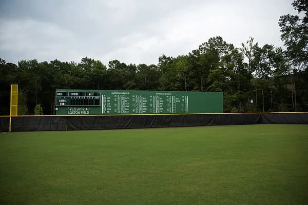 The outfield grass and green scoreboard wall of a baseball field at Wescott Park