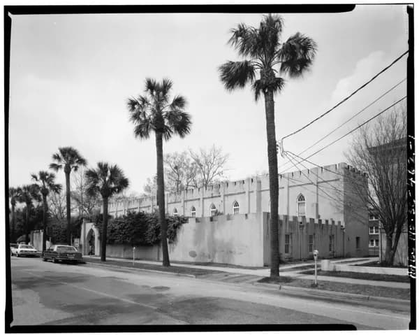 Black-and-white photograph of the crenellated Beaufort Arsenal building behind a wall, with palmetto trees along Craven Street