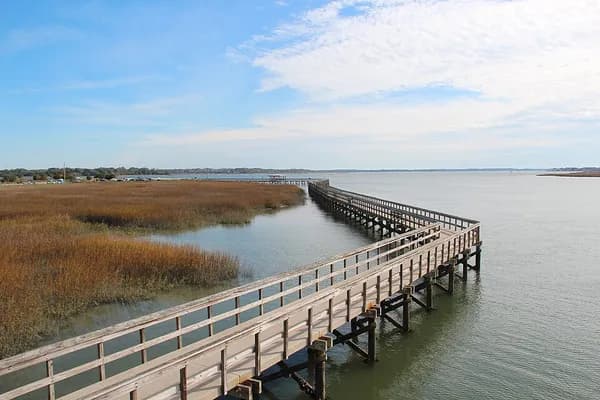 A long wooden boardwalk running out over the water beside a salt marsh at the Sands in Port Royal