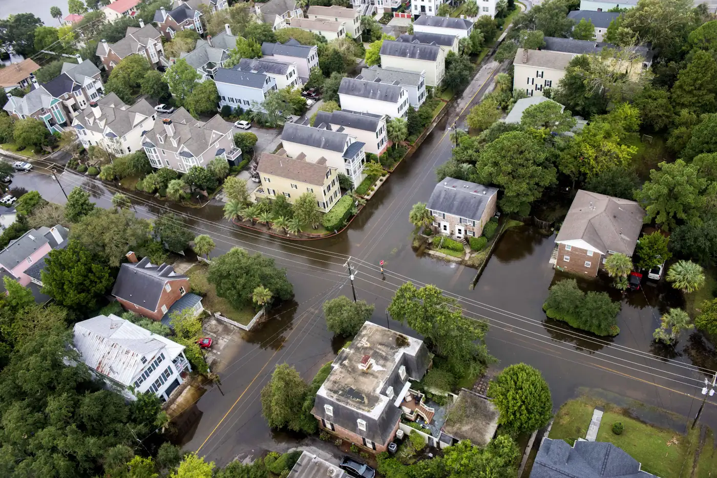 Aerial view of a Charleston-area neighborhood with floodwater covering streets and yards between houses